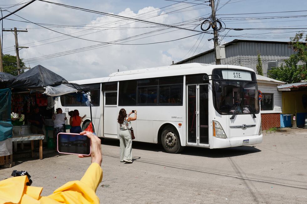 Periodistas toman fotografías de un autobús que transporta migrantes deportados de Estados...